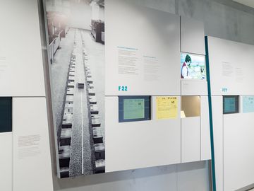 Das Bild zeigt eine Ausstellungswand, mit groflächigen Bilder, Text und Medienstationen zu den Thema Karteisystemen der Stasi.