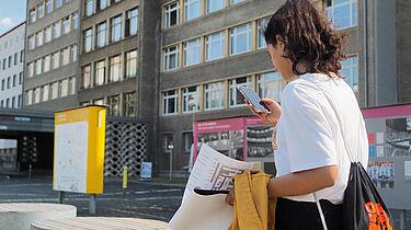 Eine Schülerin steht mit einem Smartphone in der Hand im Innenhof der 'Stasi-Zentrale. Campus für Demokratie'.