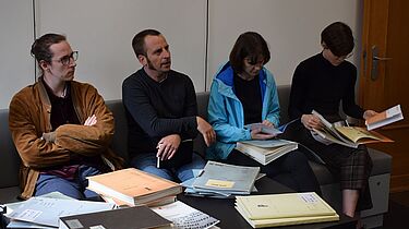 Nachwuchsjournalistinnen und -journalisten informieren sich am historischen Ort über das Stasi-Erbe Vier Personen sitzen nebeneinander. Vor ihnen liegen mehrere Beispielakten.