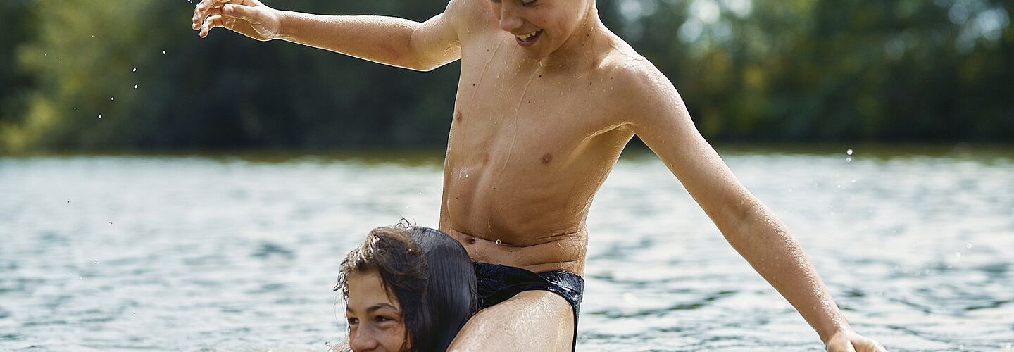 Zwei Jungen im Wasser: Ein Junge sitzt auf den Schultern des anderen.