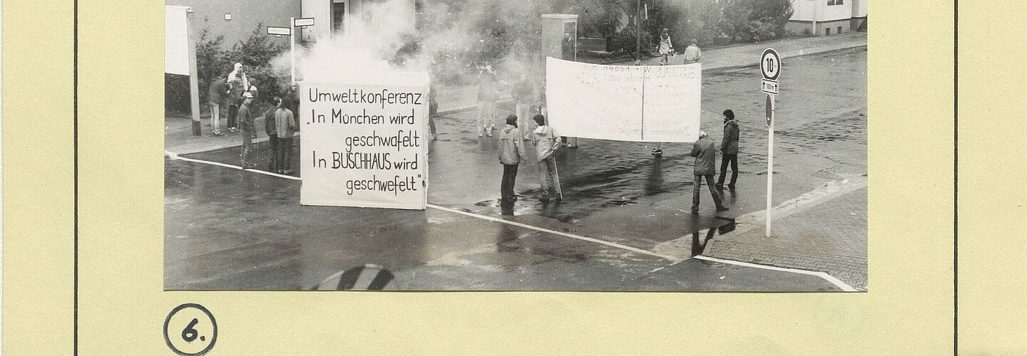 Zu sehen ist eine Seite der Akte. Darauf sind zwei Bilder aufgeklebt die eine Protestaktion der Umweltgruppe Robin Wood dokumentieren.