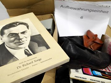 Erinnerungsstücke aus dem Traditionskabinett Auf dem Bild ist ein Karton mit verschiedenen Gegenständen zu sehen. Ein Foto von Richard Sorge, ein schwarzer Schuh und ein Stempelkasten.