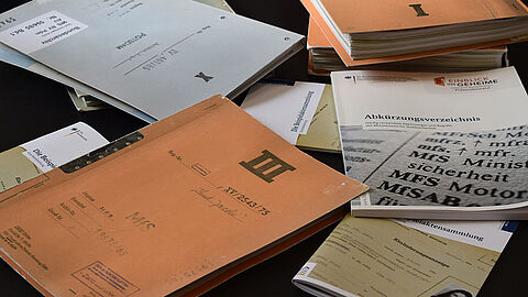 Mehrere Akten liegen auf einem Tisch.