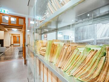 Stasi-Akten nebeneinander gestapelt in einer Vitrine