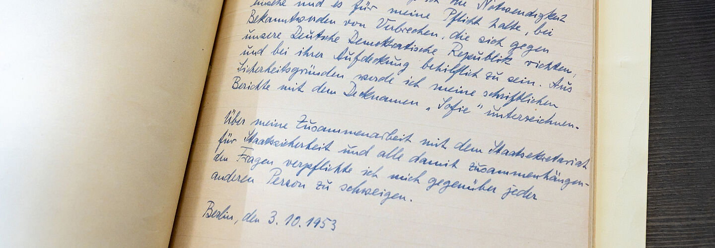 Blick in eine aufgeschlagene Akte. Zu sehen ist eine handgeschriebene Verpflichtungserklärung, die Marie Torhorst gegenüber der Stasi abgegeben hat.