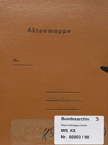 Ein rotbrauner Aktendeckel. Oben steht aufgedruckt 'Aktenmappe'. Der Name Markus Wolf ist auf einige Linie geschrieben. Unten ist ein Aufkleber des Bundesarchivs mit der Aktensignatur MfS, KS, Nr. 60003/90.