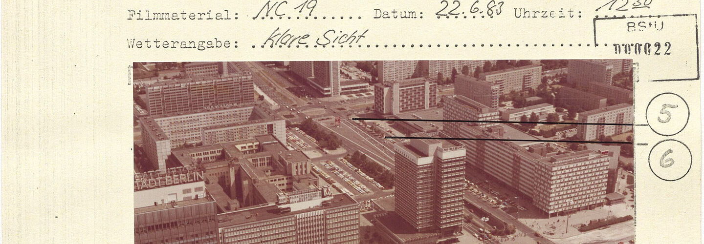Ein Ausschnitt einer Seite mit einem eingeklebten Foto. Über dem Bild sind Angaben zum Kameratyp, Film, Datum und Wetter. Das Bild zeigt die Gegend nördlich vom Fernsehturm und Alexanderplatz. Linien mit Nummern zeigen Stellen, zu denen weitere Detailaufnahmen gemacht wurden.