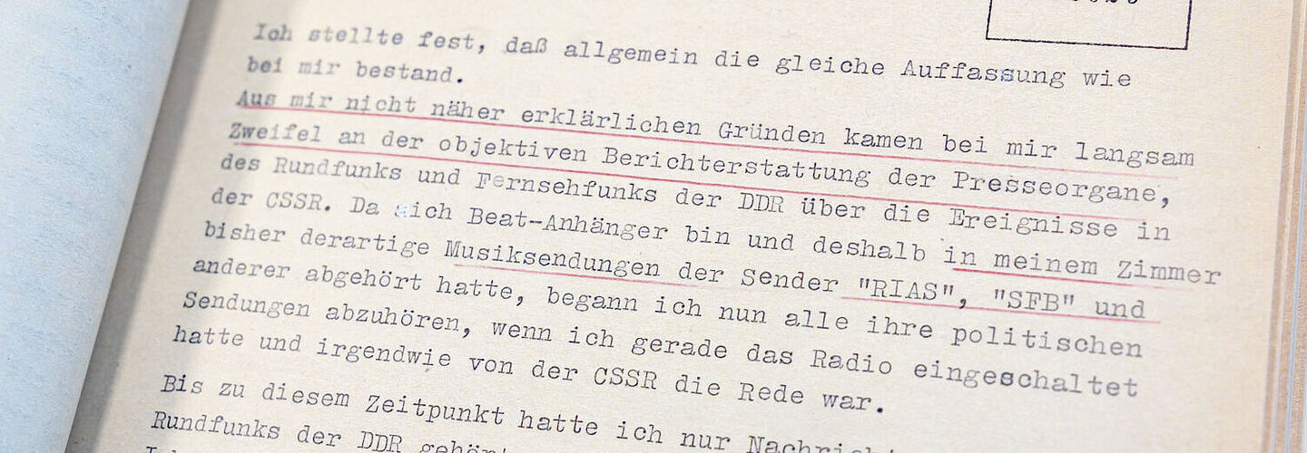 Ein Foto der aufgeschlagenen Beispielakte. Zu sehen ist ein Teil der Befragung Toni Krahls durch die Stasi. Unterstrichen ist ein Bereich, in dem Toni Krahl äußert, dass er aufgrund der Berichterstattung zur Niederschlagung des Prager Frühlings begann, den DDR-Medien nicht mehr zu vertrauen.